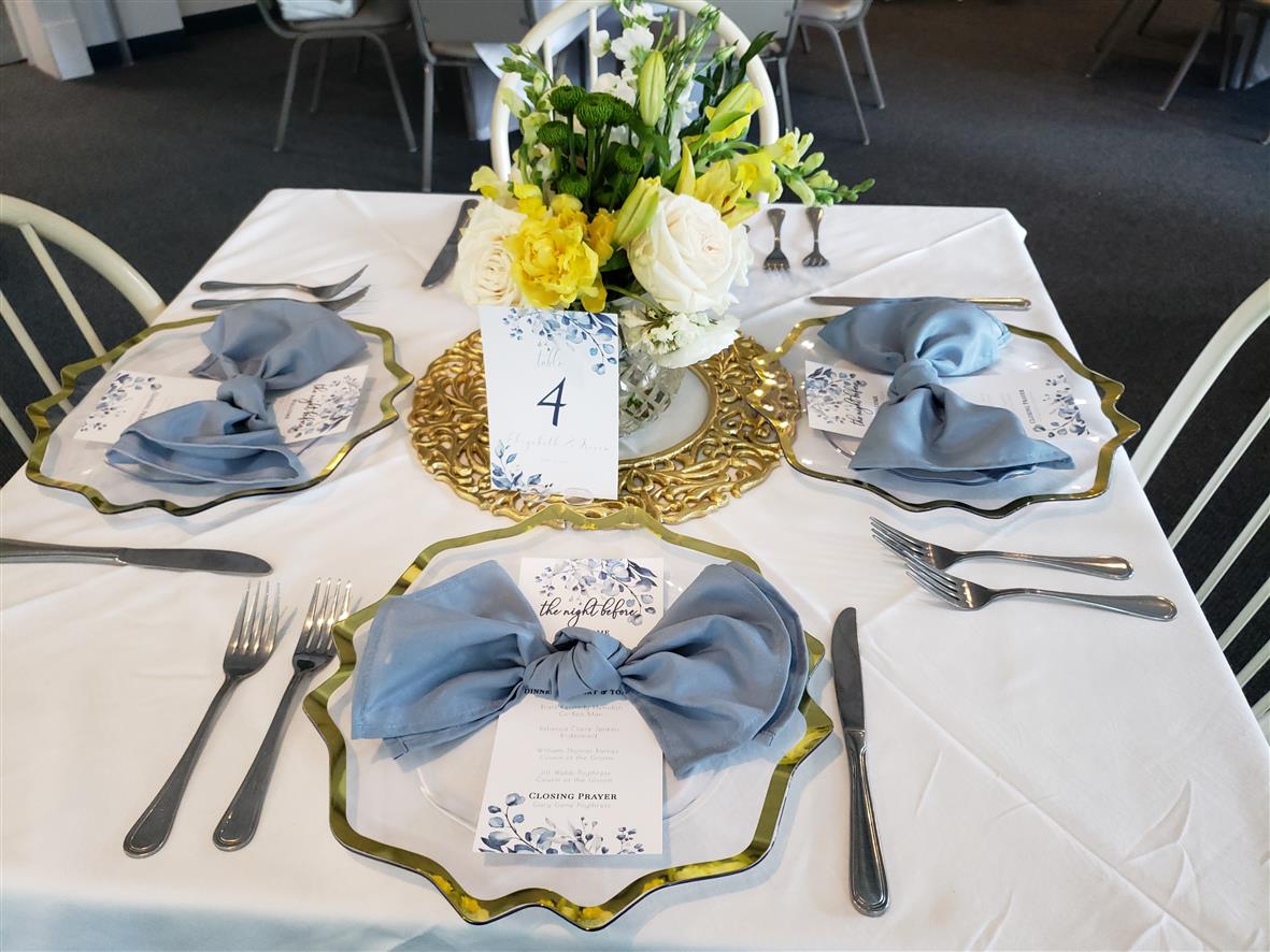Elegant banquet table with linen, floral arrangements, and blue napkins